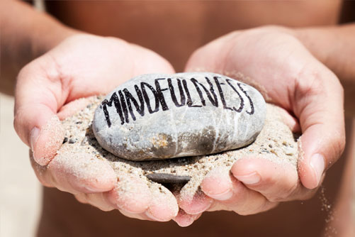 Handen houden een steen vast met het woord mindfulness